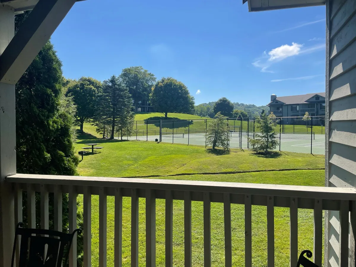 A vibrant view of tennis courts surrounded by green lawns, trees, and nearby seating areas. The scene exudes an active, social energy, highlighting opportunities for recreation and community engagement.