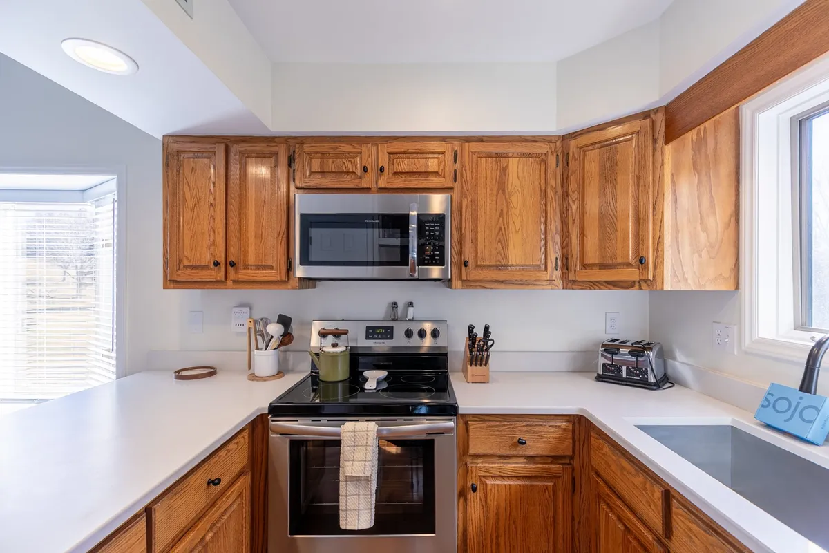 This image showcases the kitchen area, featuring modern kitchen cabinets, stainless steel appliances, a sleek countertop, and a kitchen sink. The setting is warm and welcoming, ideal for meal prep, baking, or gathering with family and friends.