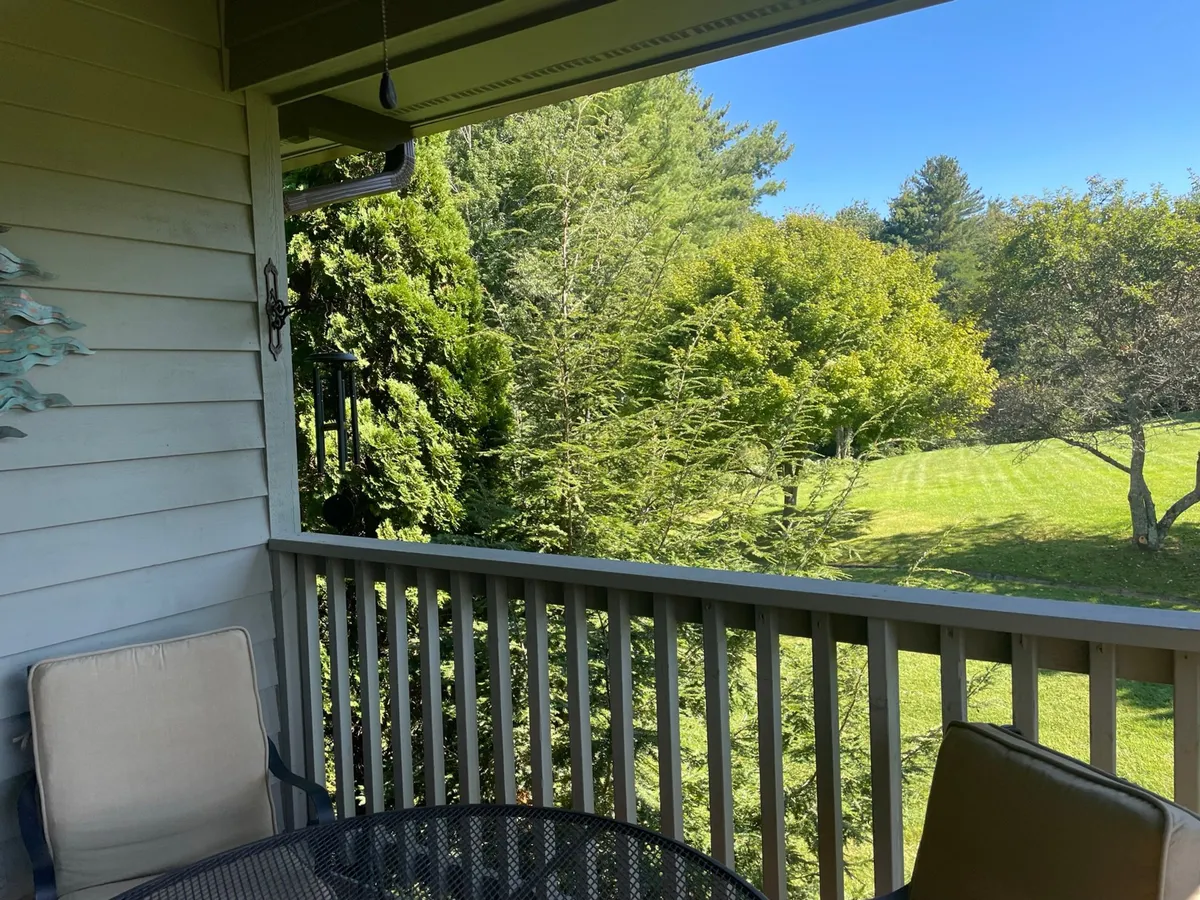 A serene balcony scene featuring comfortable outdoor seating and lush greenery beyond the railing. The view invites relaxation, morning coffee, or winding down after a day of adventure while immersed in nature.