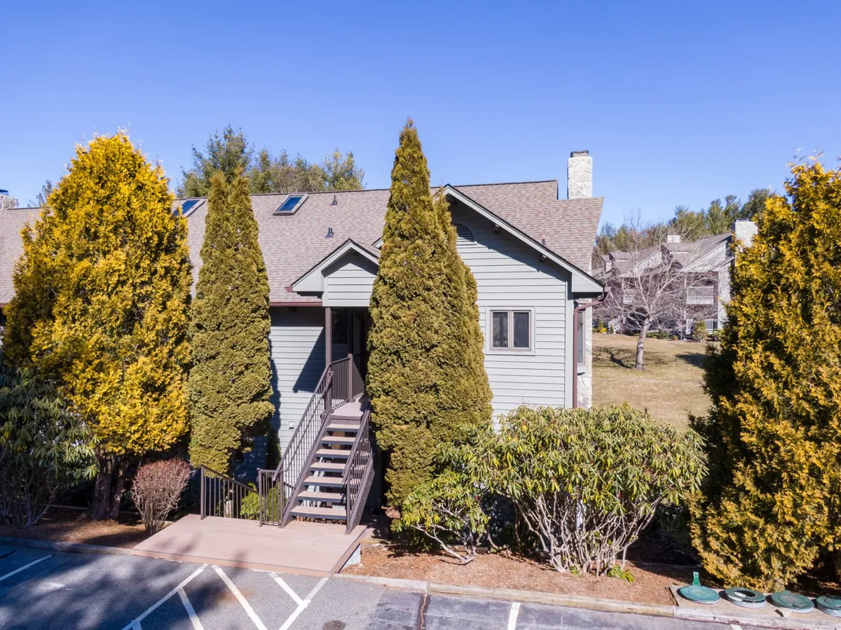 This exterior image captures the main entrance to the property, framed by tall trees and a well-maintained lawn, inviting families to step outside and explore. The staircase leading to the entrance hints at easy access to all resort amenities and outdoor spaces.